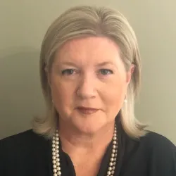 White woman with blonde hair and pearl necklace