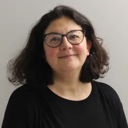 White woman with short black hair and glasses 