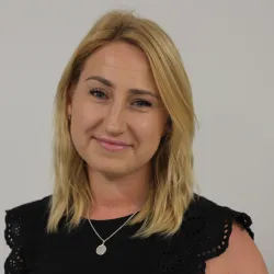 Photograph of a white woman with blonde hair smiling