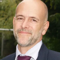 Photograph of a white man in a suit smiling