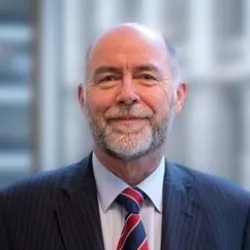 Photograph of a man in a suit smiling