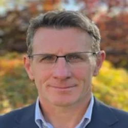 Photograph of a white man with glasses on smiling