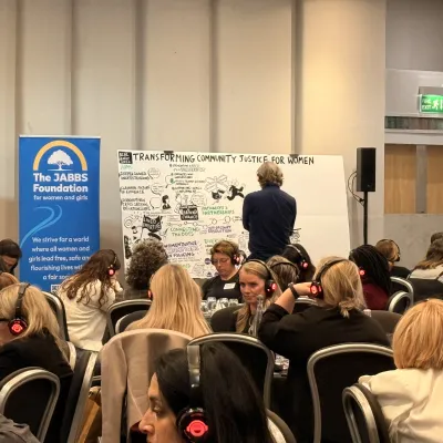 Photograph from the conference of people sat in a room, with the live illustration being drawn