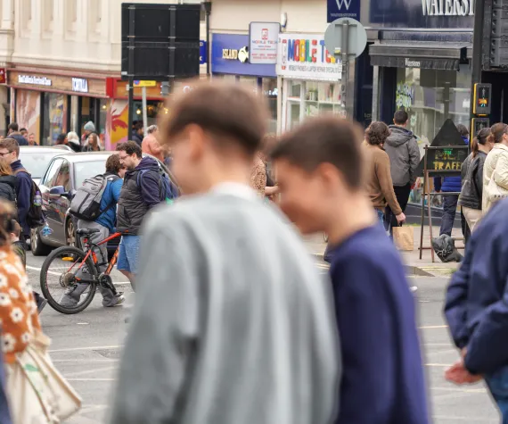 photograph on a high street with two children/ young people stood facing the other way in the foreground but out of focus