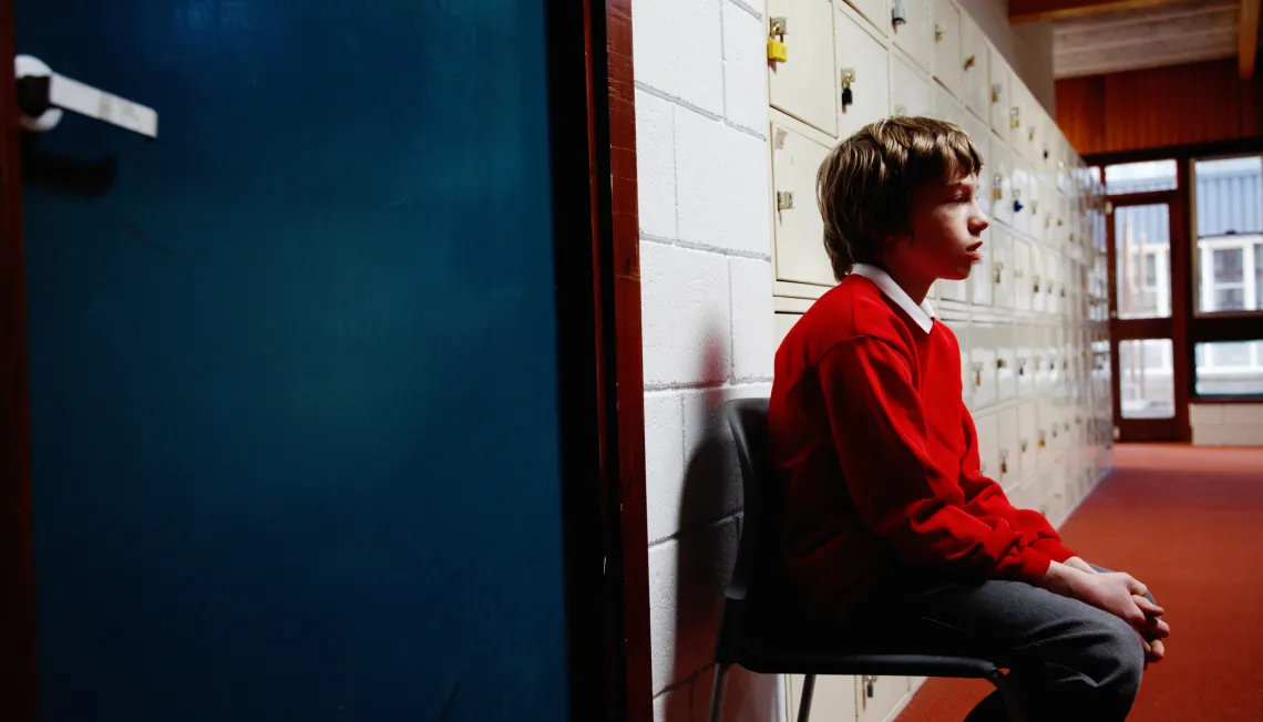 School boy waits in corridor