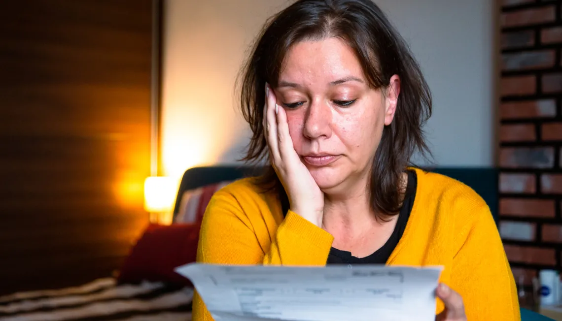 A woman appearing anxious whilst reading a letter.