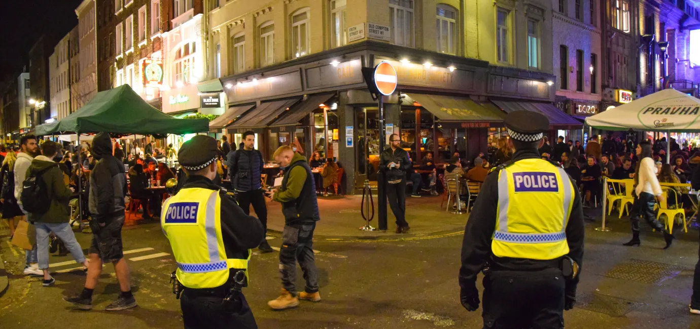 Two police officers on a busy street at night