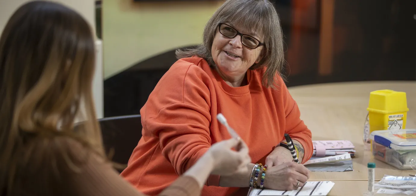 Woman in orange top speaking to another woman