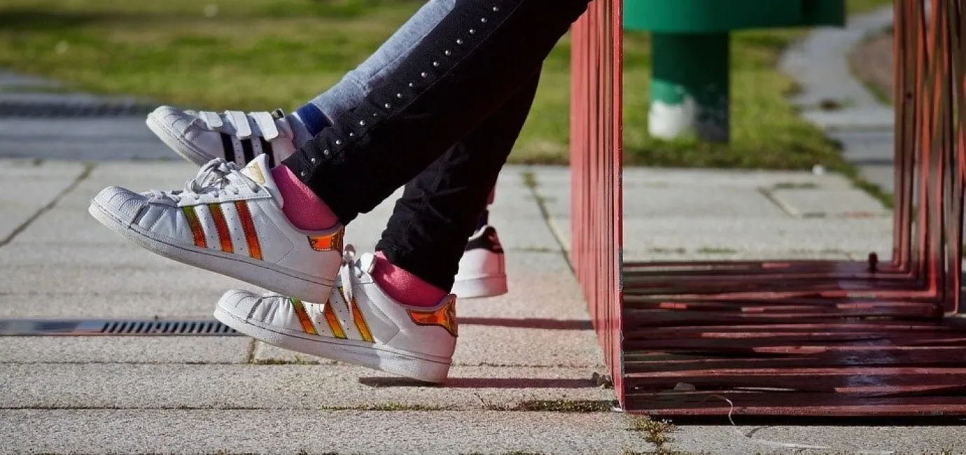 Photograph of young people's shoes (who are sat on a bench)