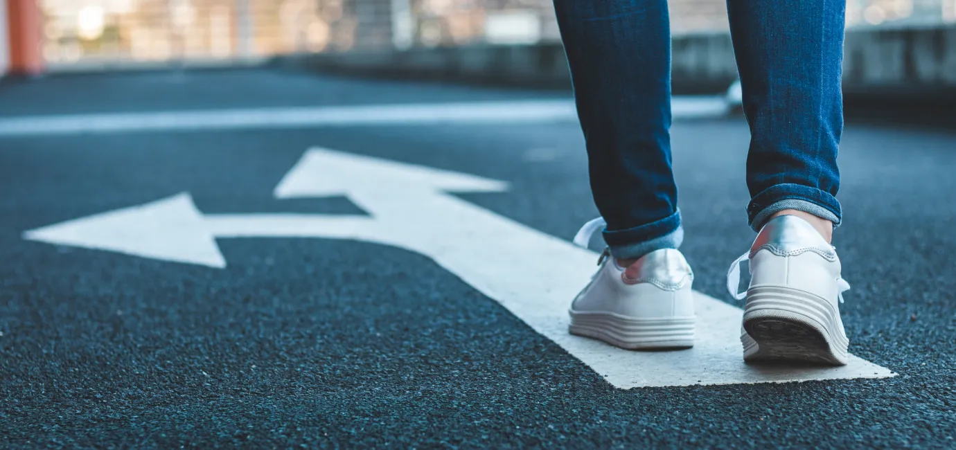 Image of someone walking up to a diversion sign on the road - only their feet and lower legs visible